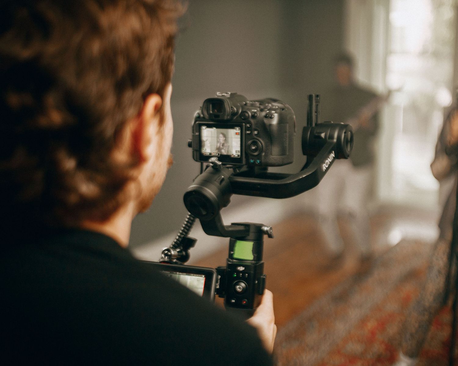 Camera operator using a professional gimbal stabilizer to film indoors.