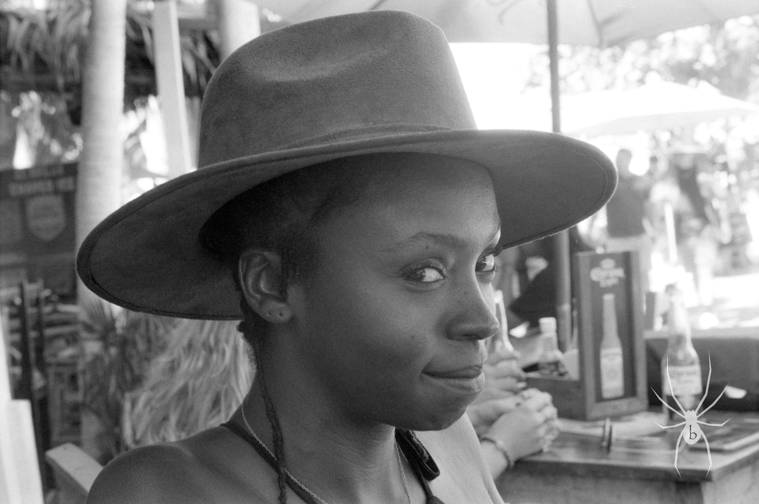 Black and white portrait of a person wearing a wide-brimmed hat in natural light.