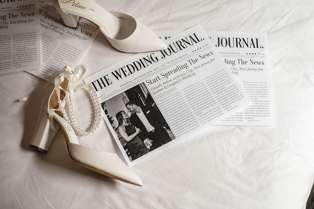 Wedding details including white bridal shoes and newspaper clippings on white fabric.