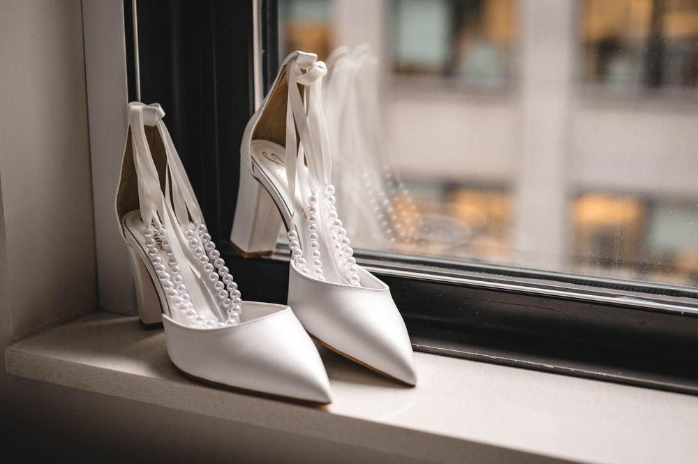 Wedding shoes and accessories artistically arranged by a window.