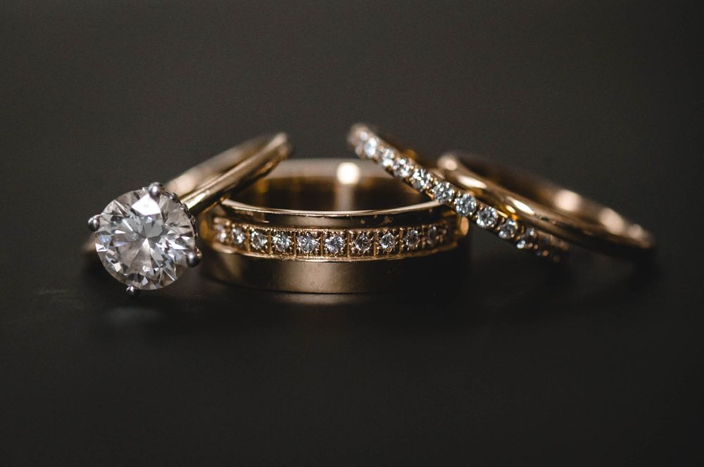 Close-up of diamond wedding rings and bands on dark background.