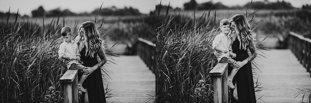 Black and white diptych of figures on a wooden boardwalk among tall reeds in a wetland setting.