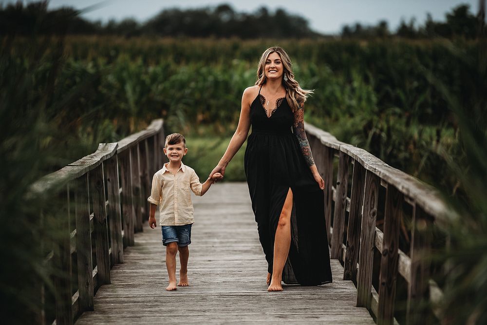 Walking together on a wooden bridge surrounded by tall marsh grasses.