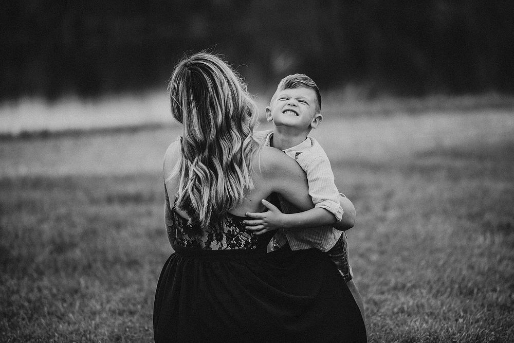 Candid black and white portrait capturing laughter and embrace in an outdoor setting.
