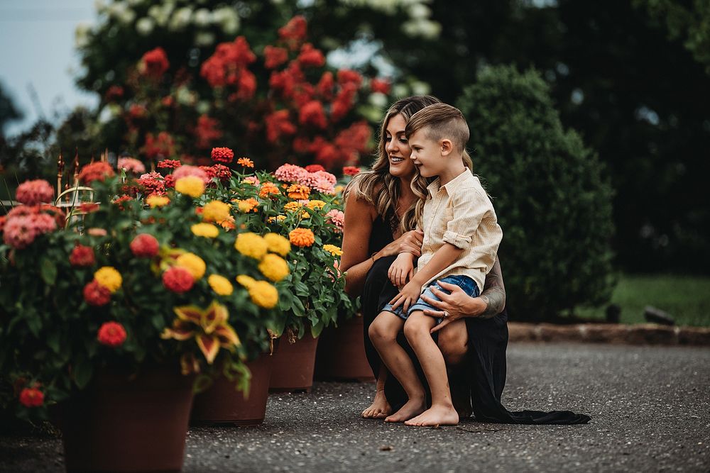 A tender moment shared between two people near colorful flower pots in a garden.
