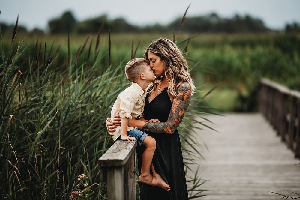 A heartwarming moment captured on a wooden boardwalk surrounded by tall grass.