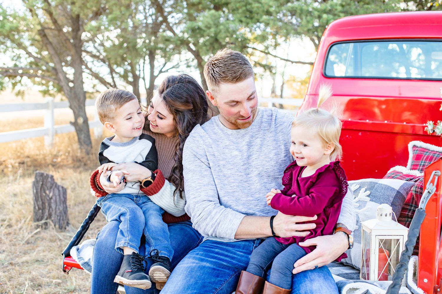 Parents snuggle their toddler children in the bed of a vintage truck in Colorado Springs, Colorado.