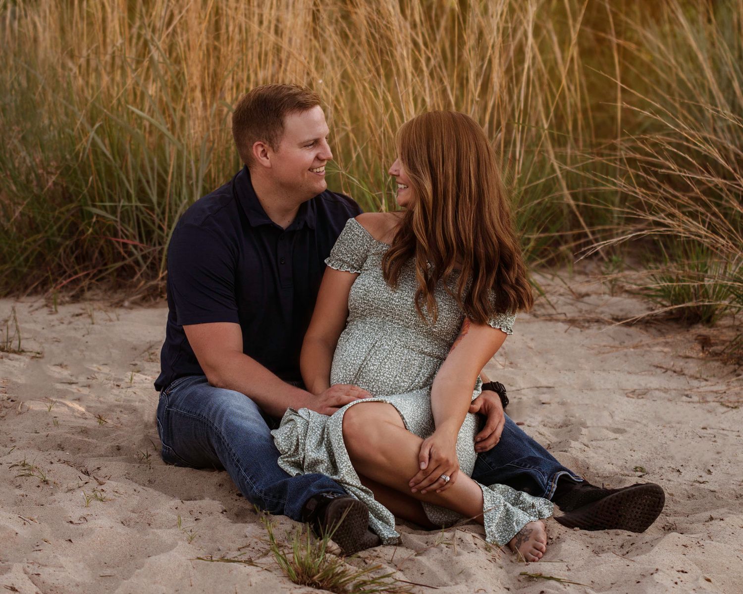 Intimate couple portraits on sandy beach with sea grass during golden hour.