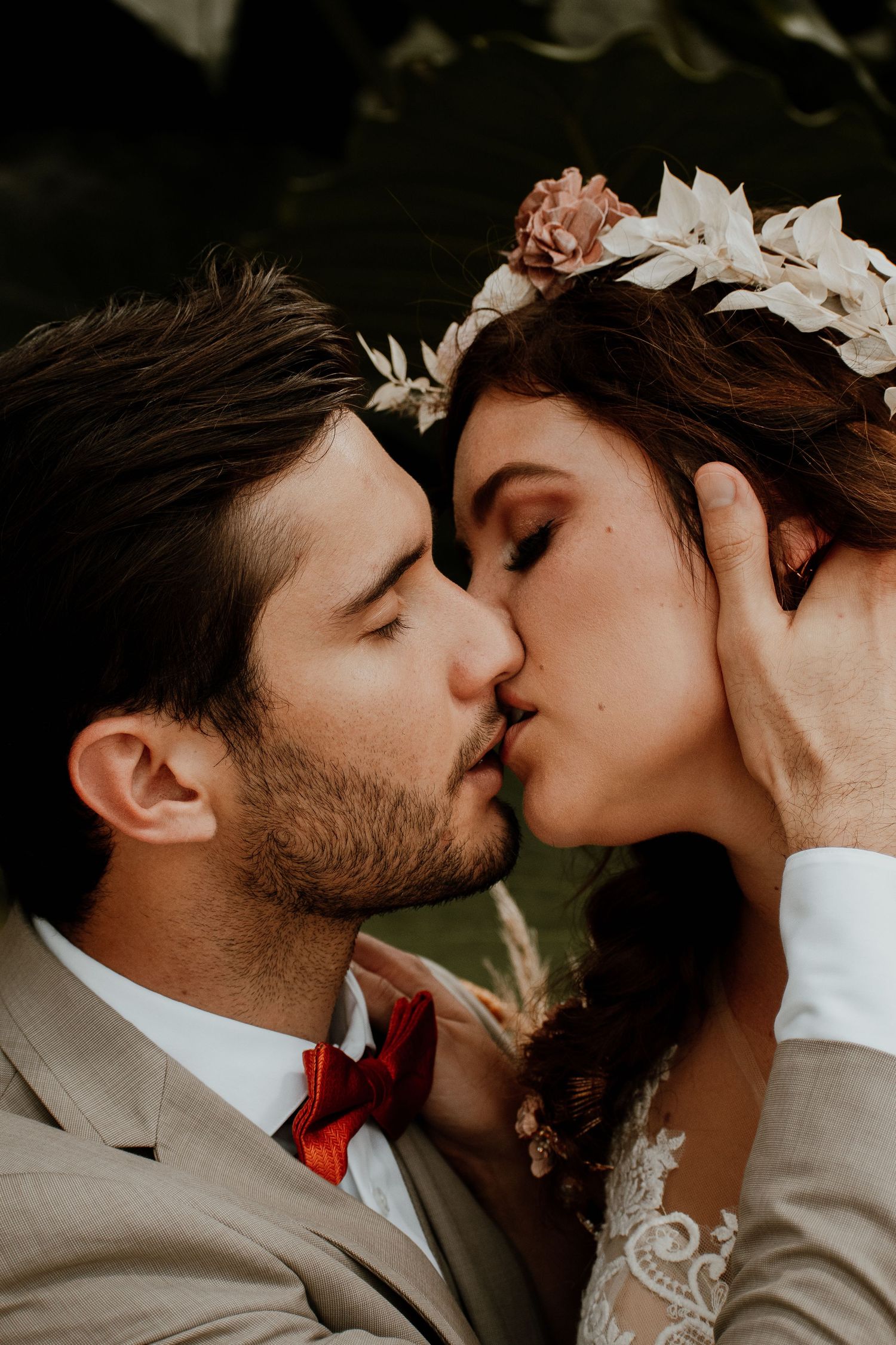 Romantic close-up of newlyweds sharing an intimate kiss with soft lighting.