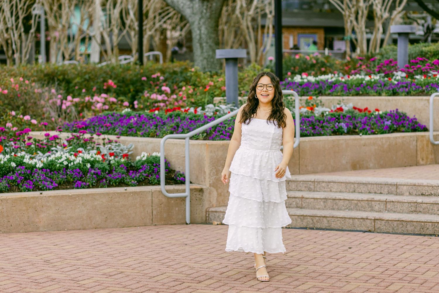 a high school senior girl in a white dress in front of colorful flowers