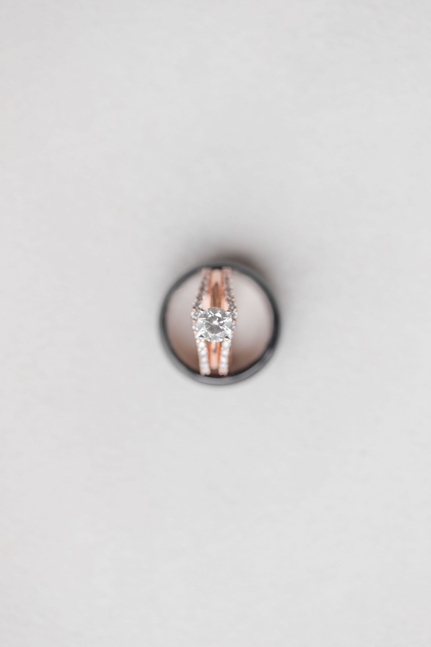 Close-up of rose gold engagement ring with diamond solitaire on white background.