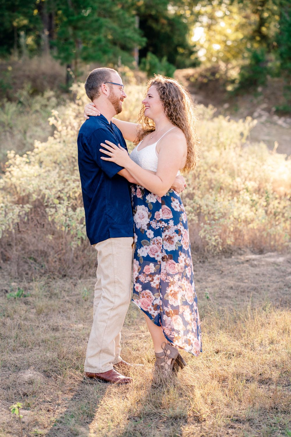 A joyful couple embraces in a sunlit field during golden hour.