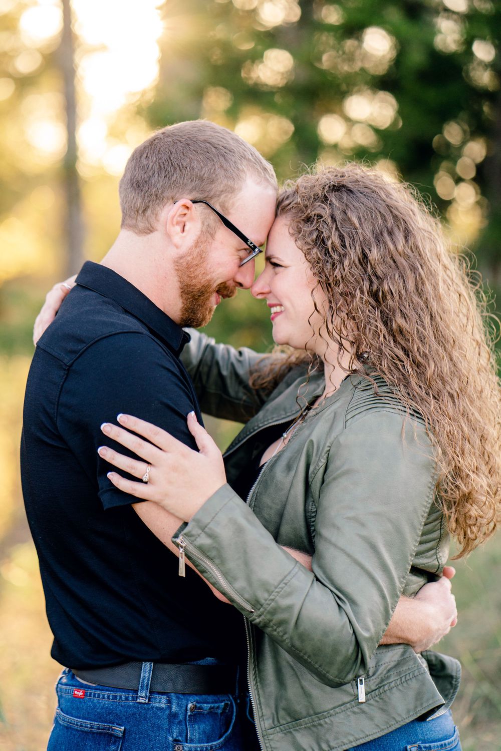Couple embracing tenderly outdoors with golden sunlight filtering through trees.