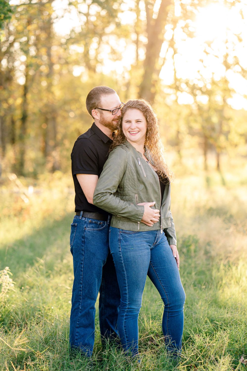 Sweet outdoor portrait of a couple in casual wear standing together in golden evening light.