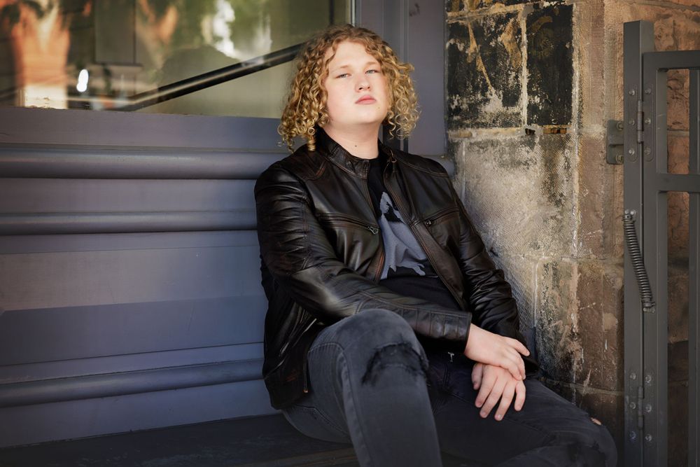 Person in leather jacket relaxes on stone steps.