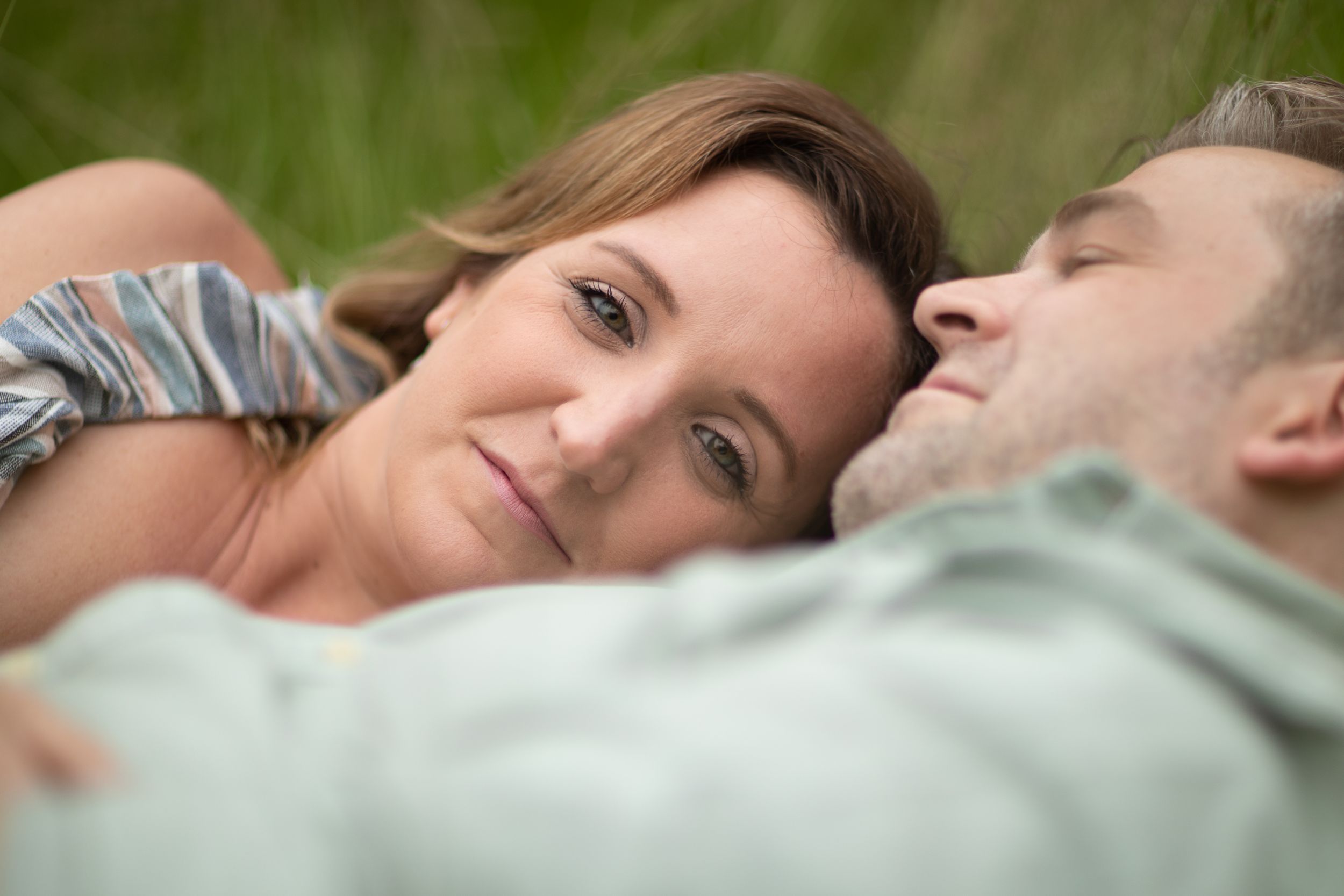 future bride relaxing in long grass engagement ring at pre wedding engagement photoshoot