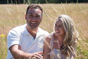 engaged couple laughing in field
