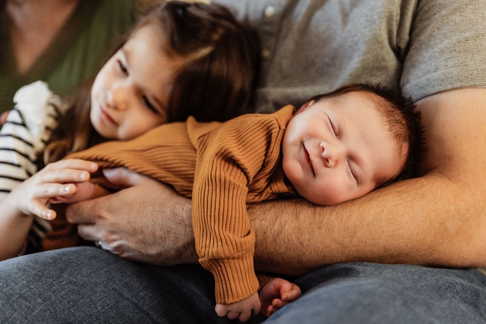 Peaceful newborn napping on parent's chest in warm natural lighting.