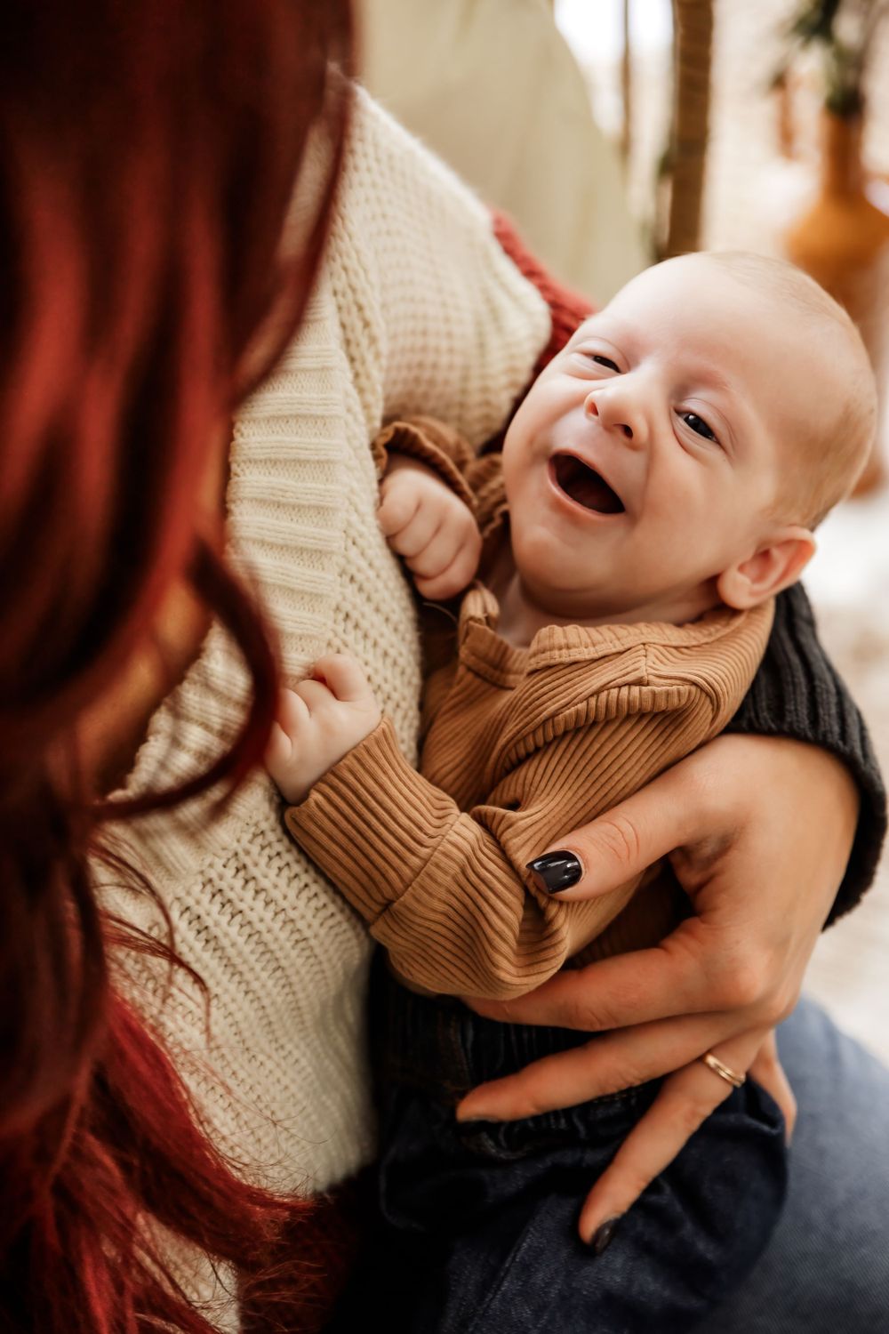 Close-up photos of a baby laughing and smiling while wearing a brown knit sweater.