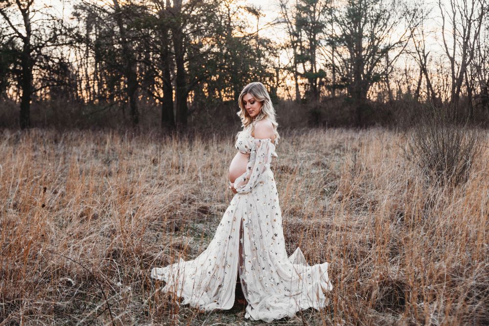 Outdoor maternity photo series with a flowing white dress against a natural landscape.