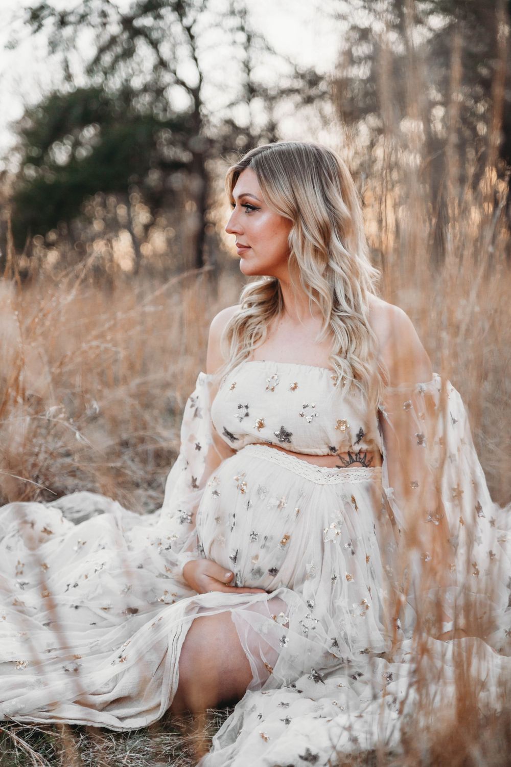 A flowing white floral dress captured in a dreamy outdoor photoshoot with golden sunlight filtering through tall grass.