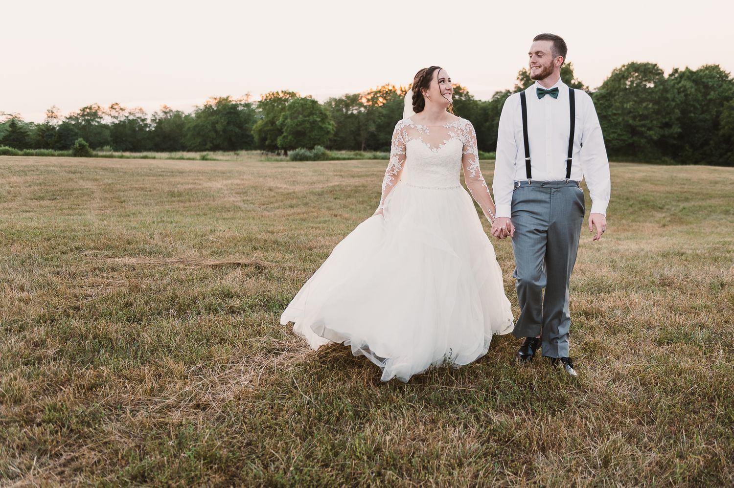 Bride and groom walking through a field