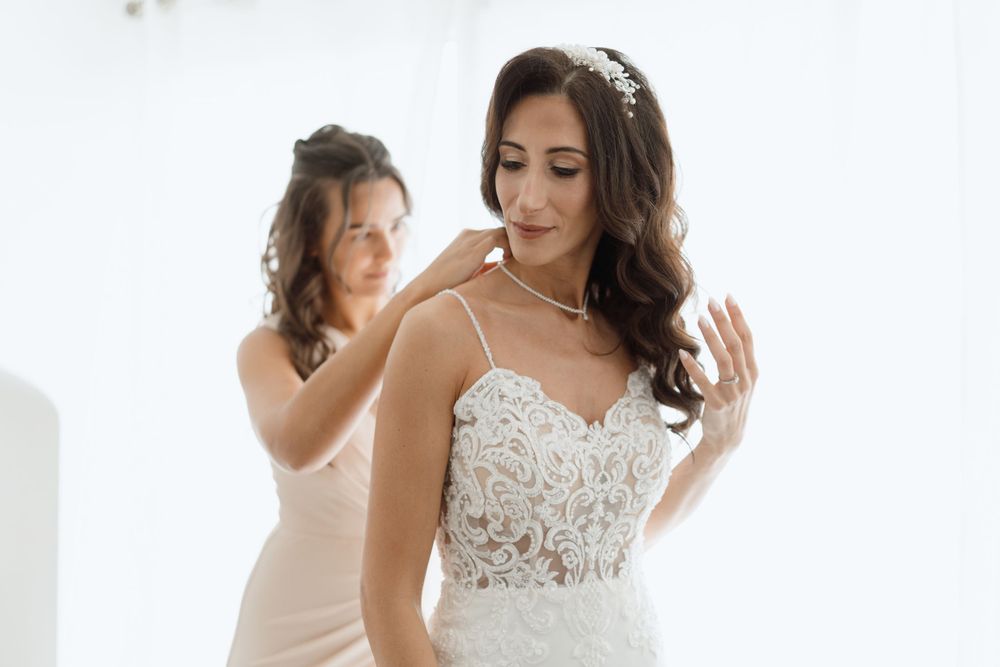 Elegant bridal preparation moments captured in white minimalist room.