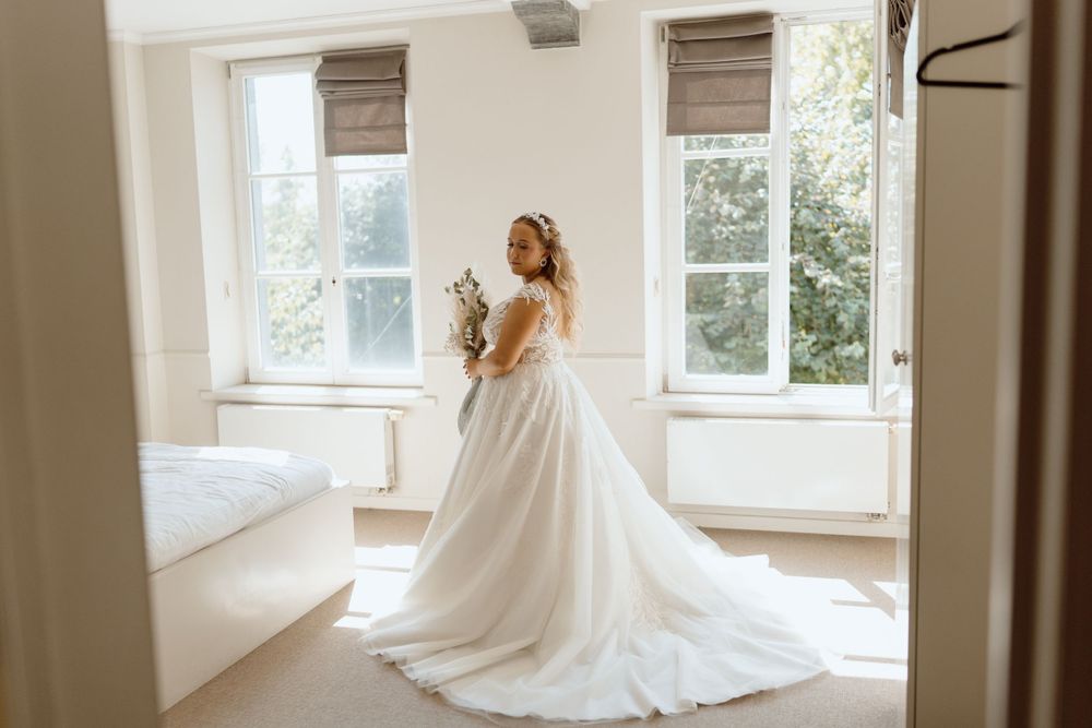 Ethereal bridal portraits in sunlit room with flowing white wedding dress.