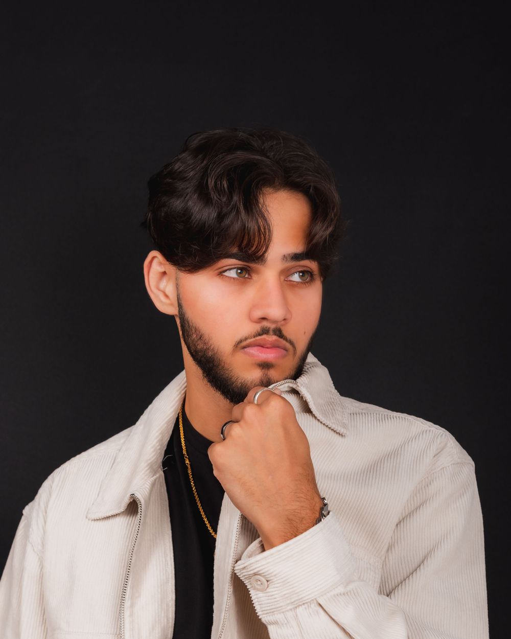 Portrait of a man wearing a beige corduroy jacket against a dark background.