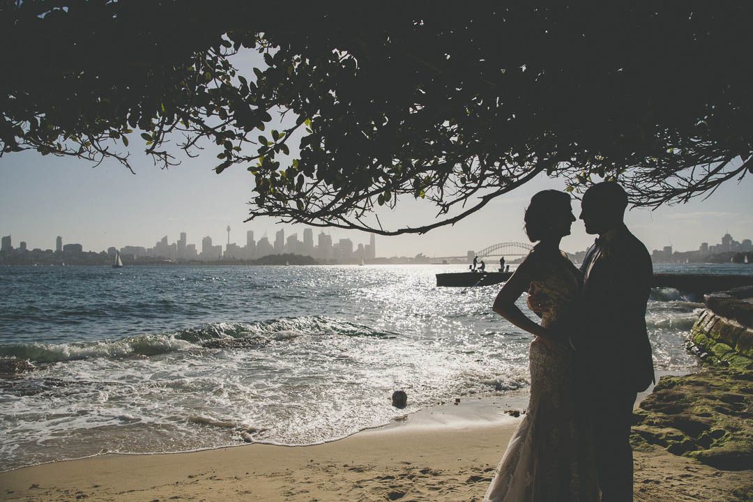 Silhouettes of people enjoying a beach with city skyline visible in the distance.