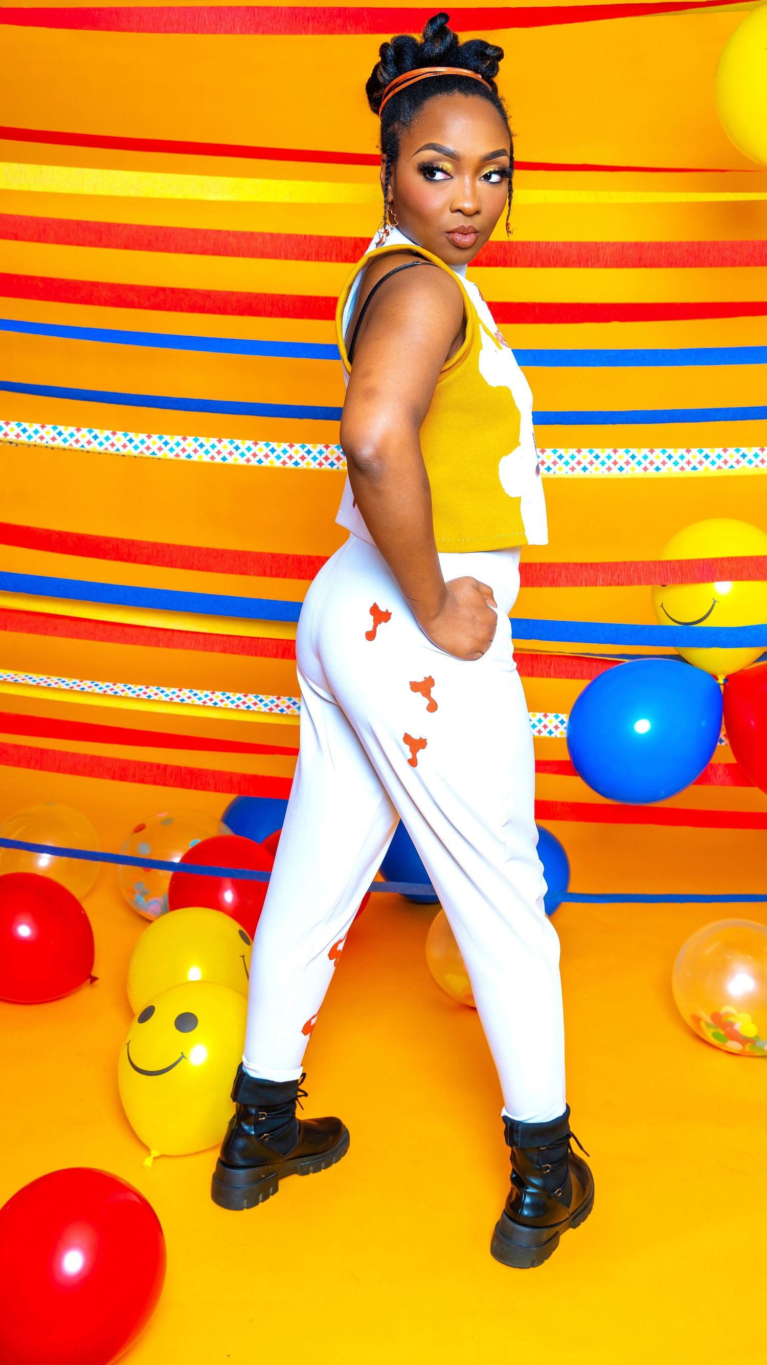 Vibrant portrait against colorful striped backdrop with balloons and playful party decorations.