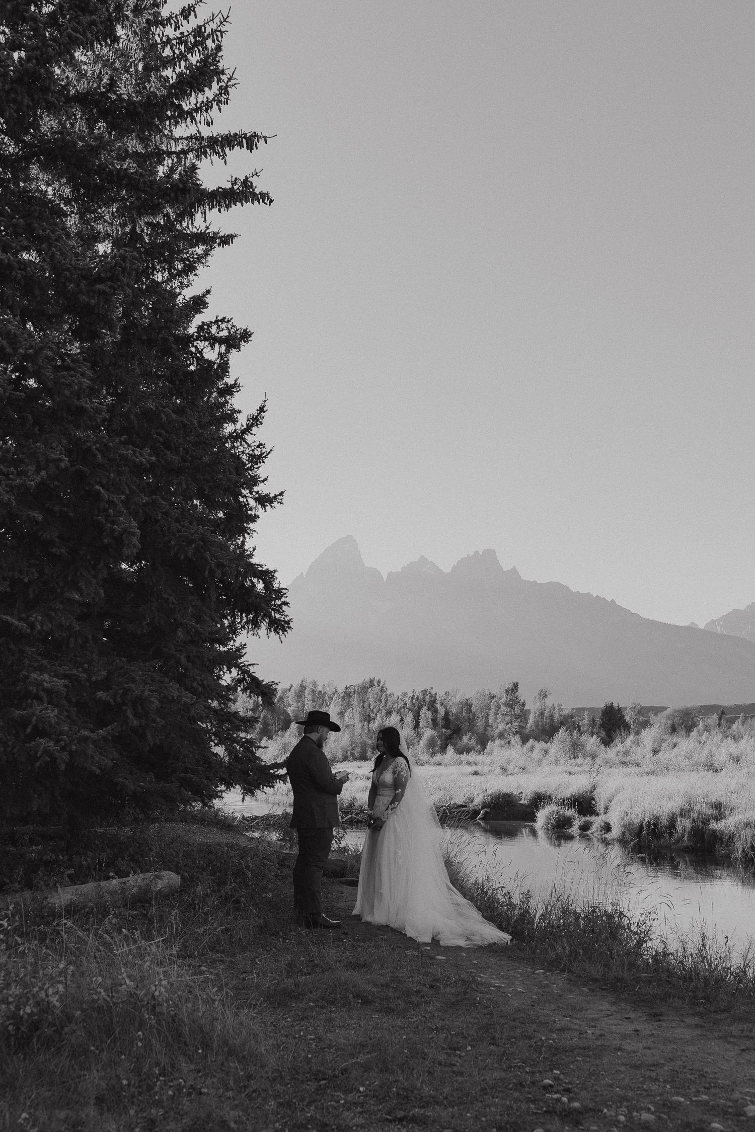 A black and white wedding photo with mountain peaks in the background.