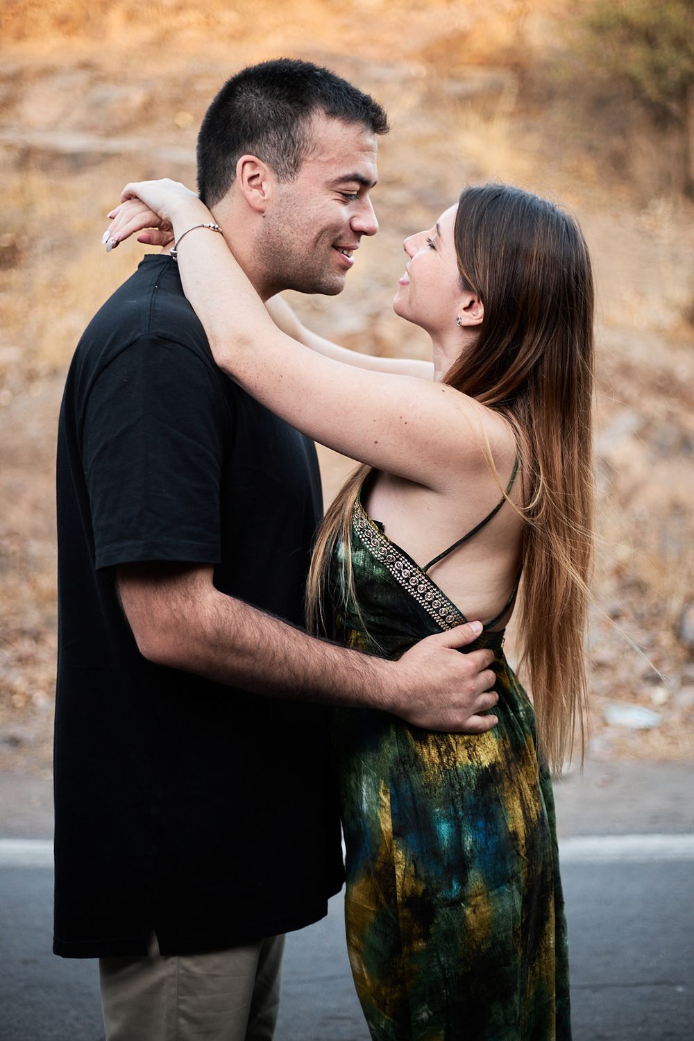 A couple embraces intimately on a scenic mountain road at sunset.