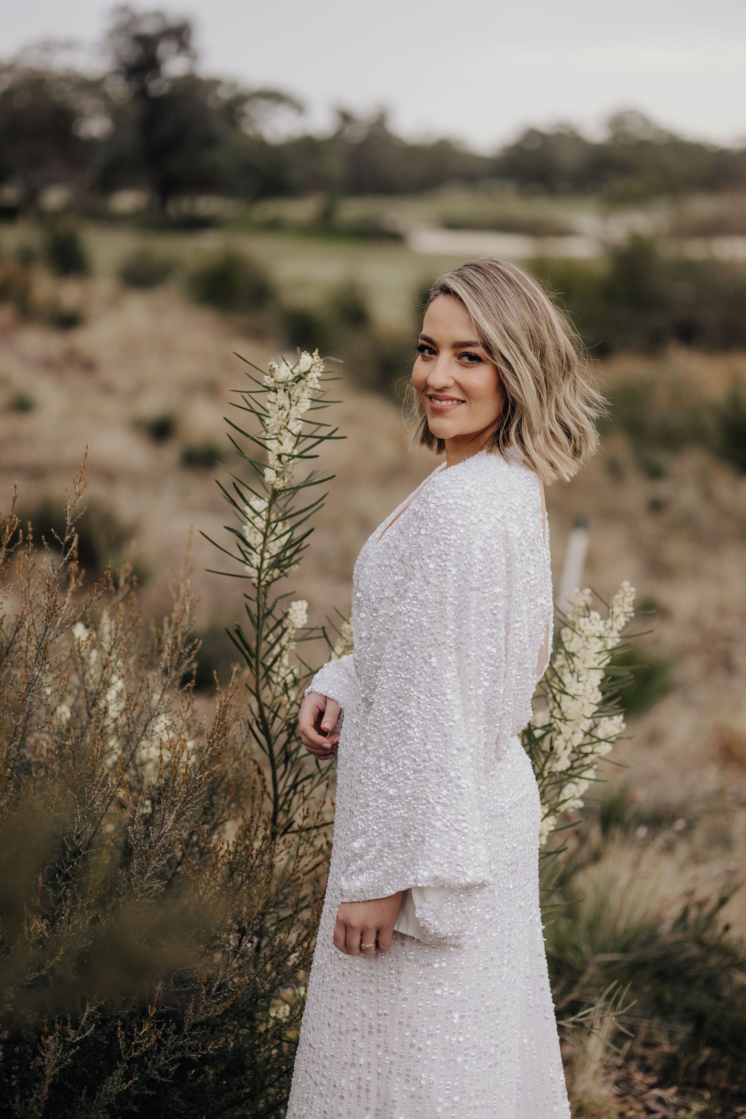 Sequined white dress captured in desert landscape with natural brush and mountain backdrop.