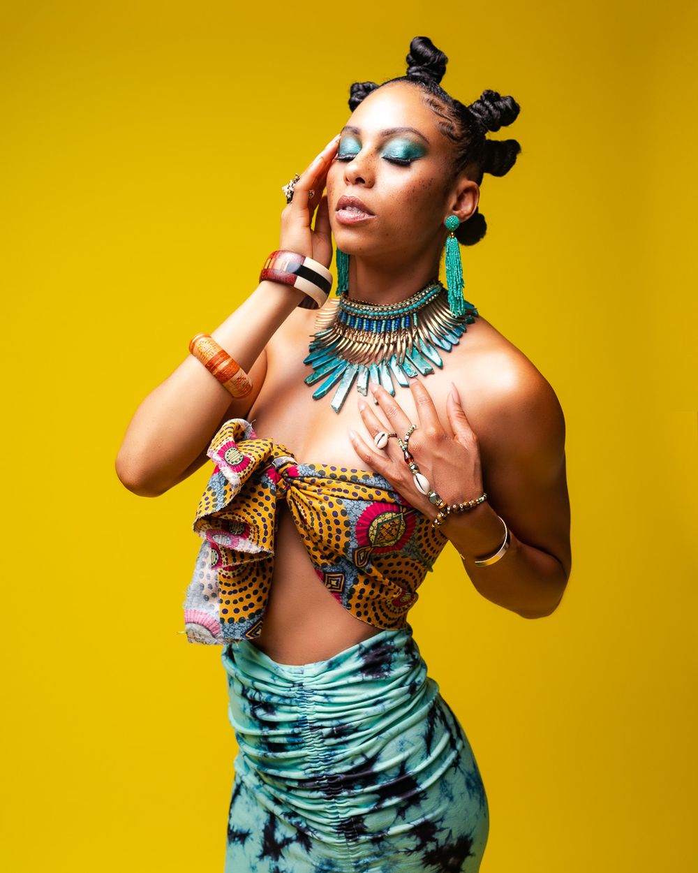 Fashion portrait against yellow background featuring tribal jewelry and colorful printed fabric.