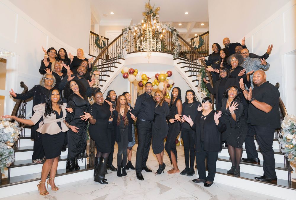 Fun group photo with team members jumping and posing on grand staircase with festive decorations.