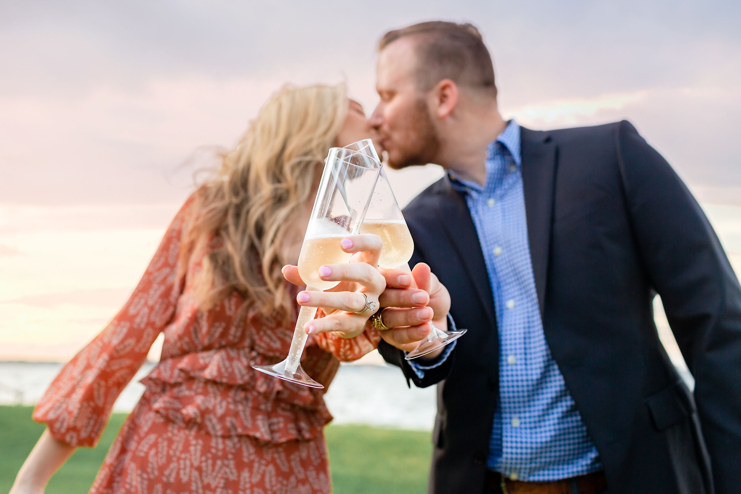 Couple kisses and touches their champagne glasses together after a surprise engagement on Lake Conroe in Texas.
