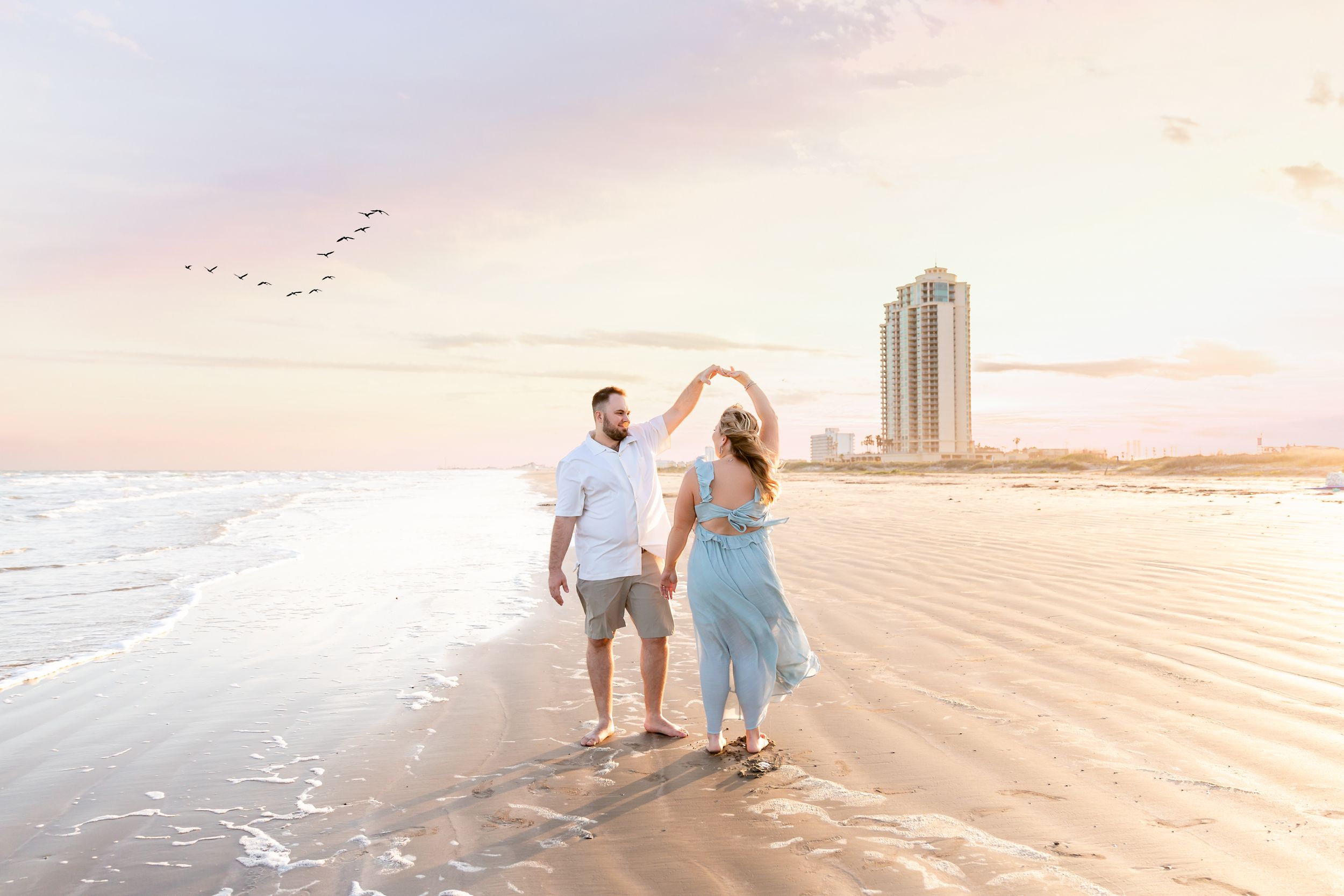 Couple dances on the beach during their engagement session in Galveston, TX.