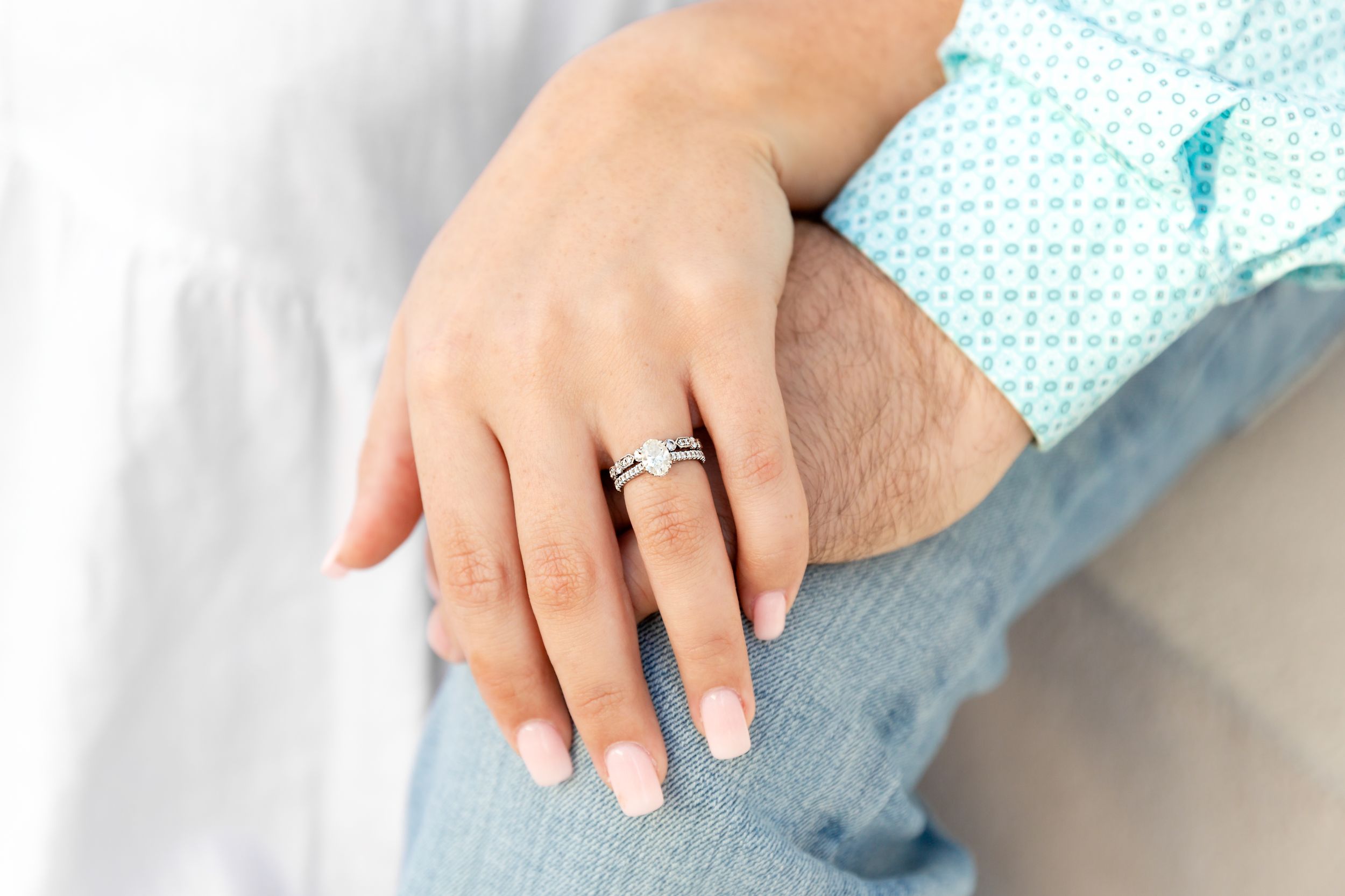 Engaged couple's hands intertwined with focus on the engagement ring in Galveston, TX.