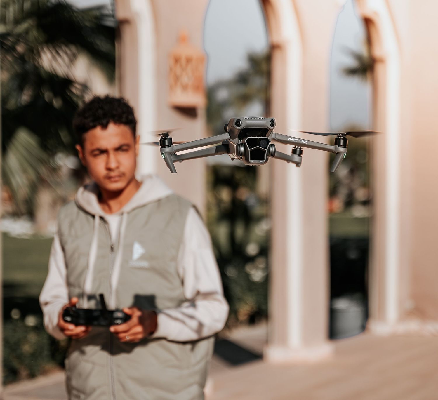 DJI drone hovering in front of Mediterranean style architecture.