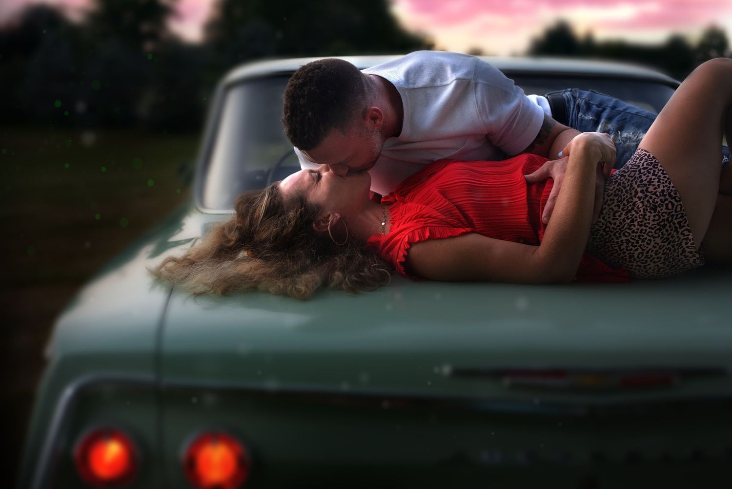 Portrait of husband and wife kissing on classic car.