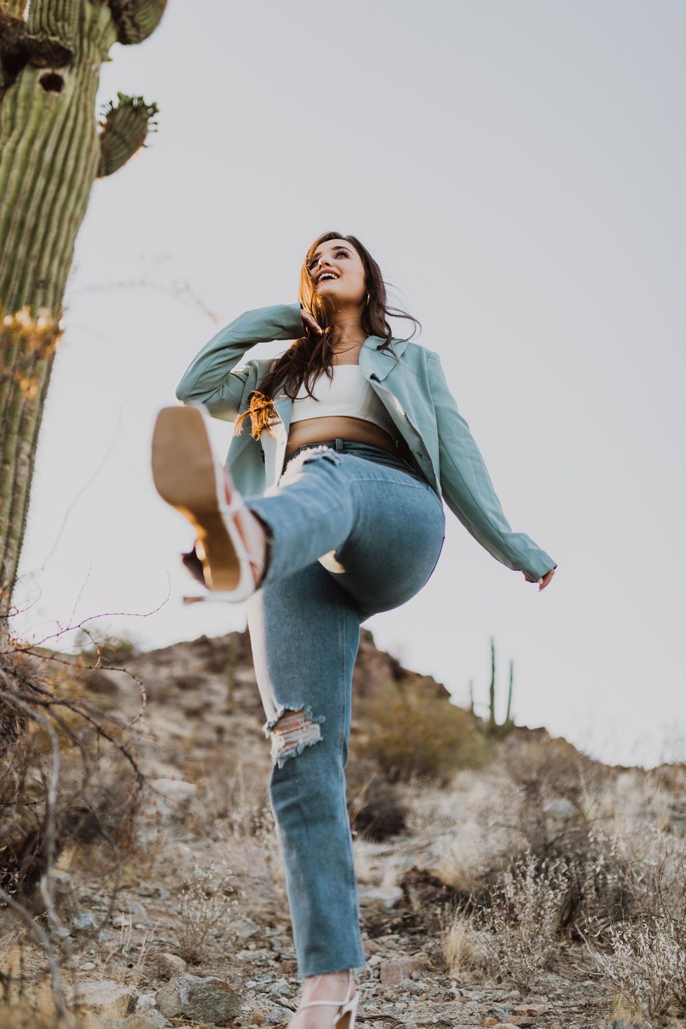 Dynamic poses near desert cacti wearing mint jacket and casual attire.