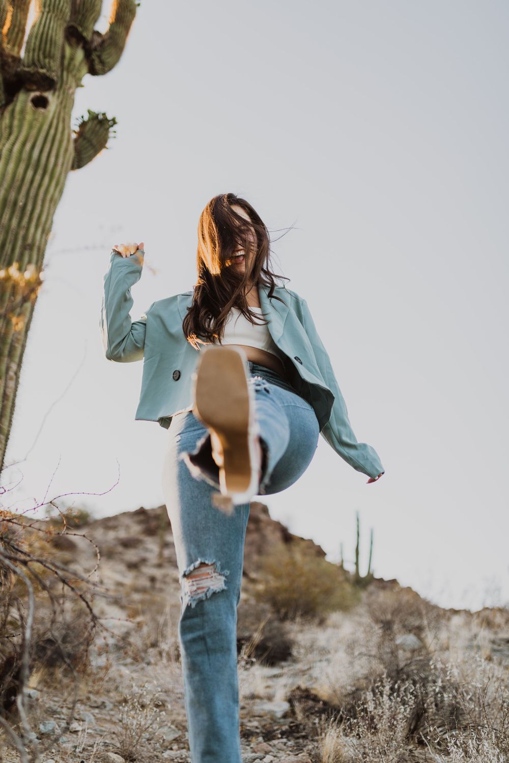 Playful movement shots in desert landscape with mint blazer and jeans.