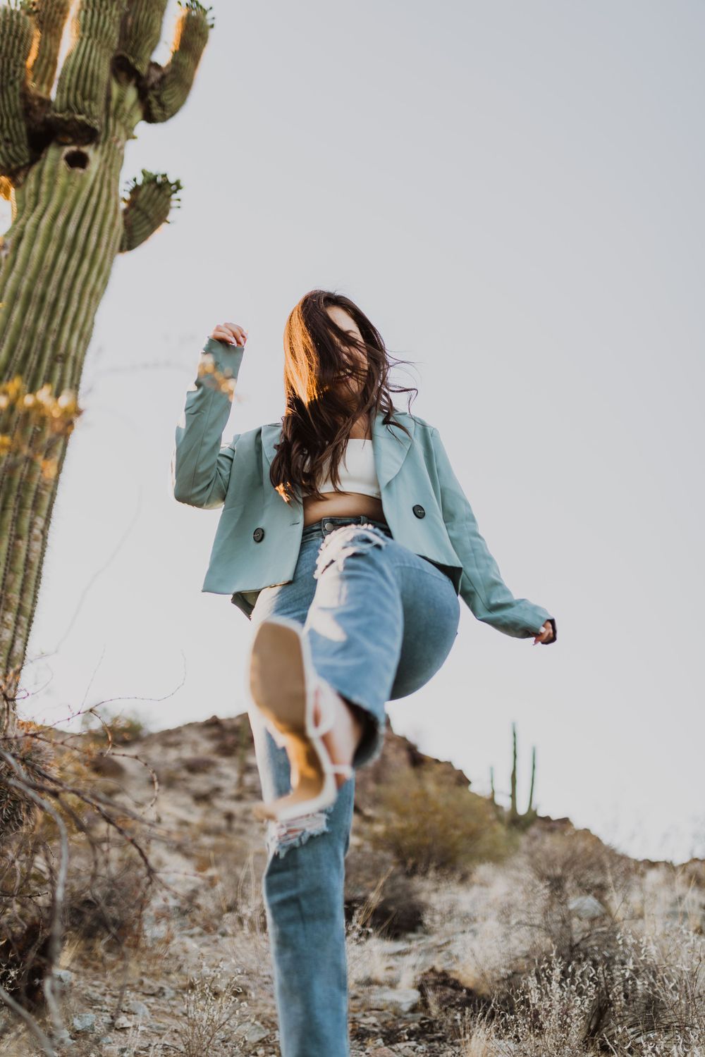 Energetic dance-like poses captured against desert scenery and saguaro cactus.