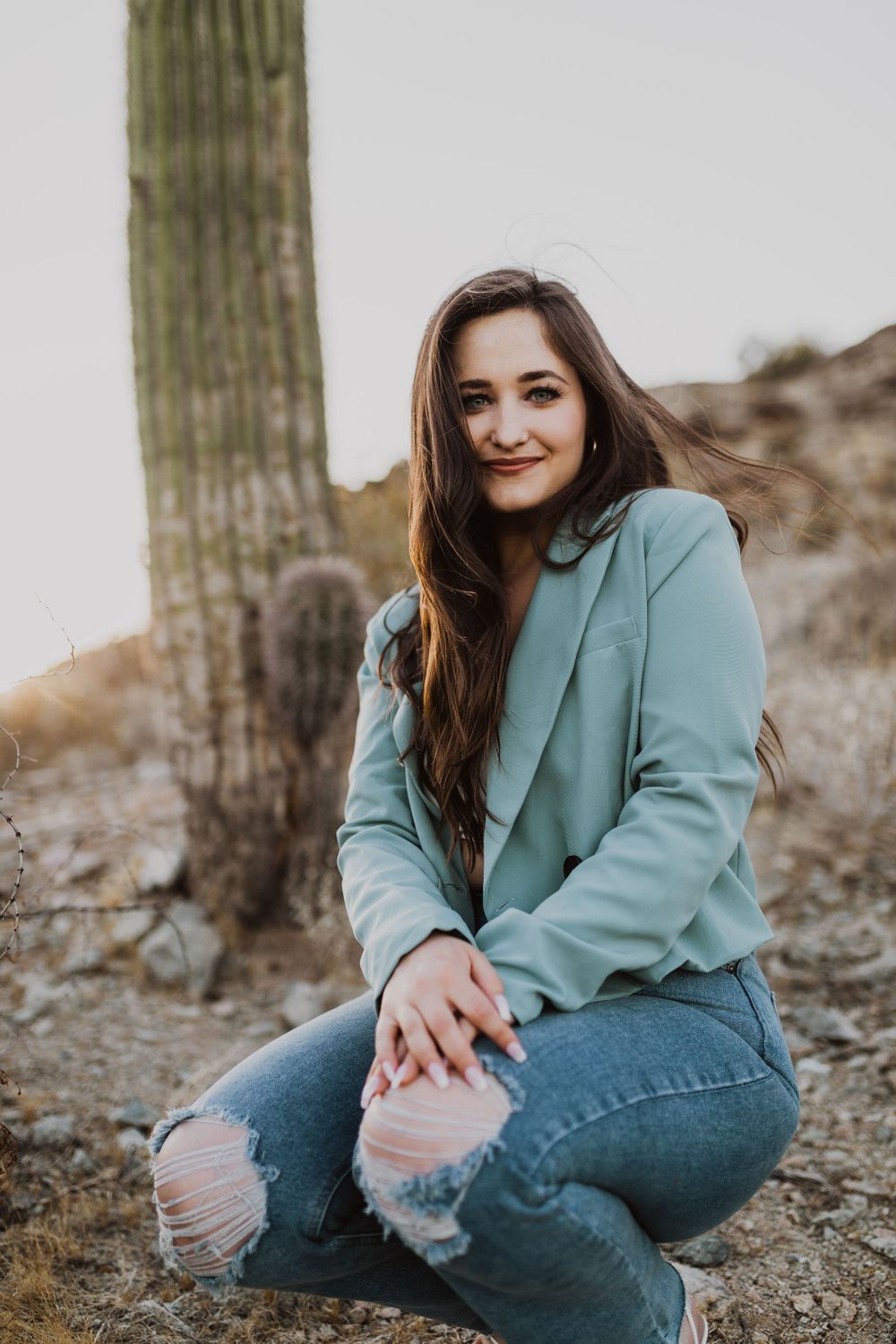 Natural lifestyle poses near saguaro cactus in casual denim and mint blazer.