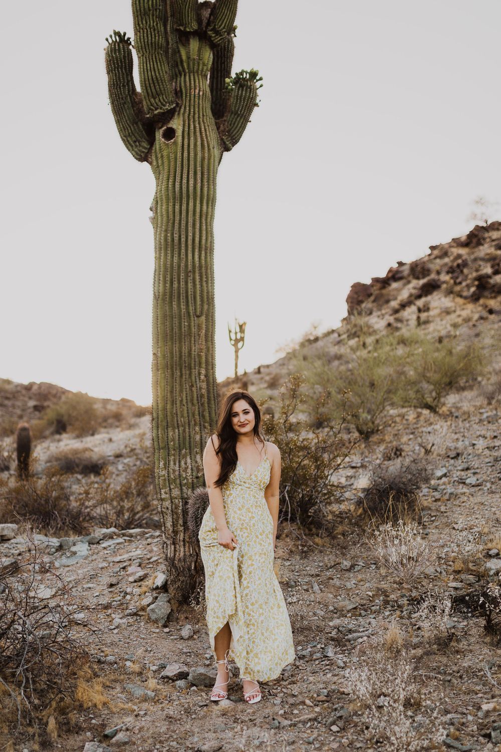 Fashion shoot in desert landscape with floral dress and towering saguaro cactus.