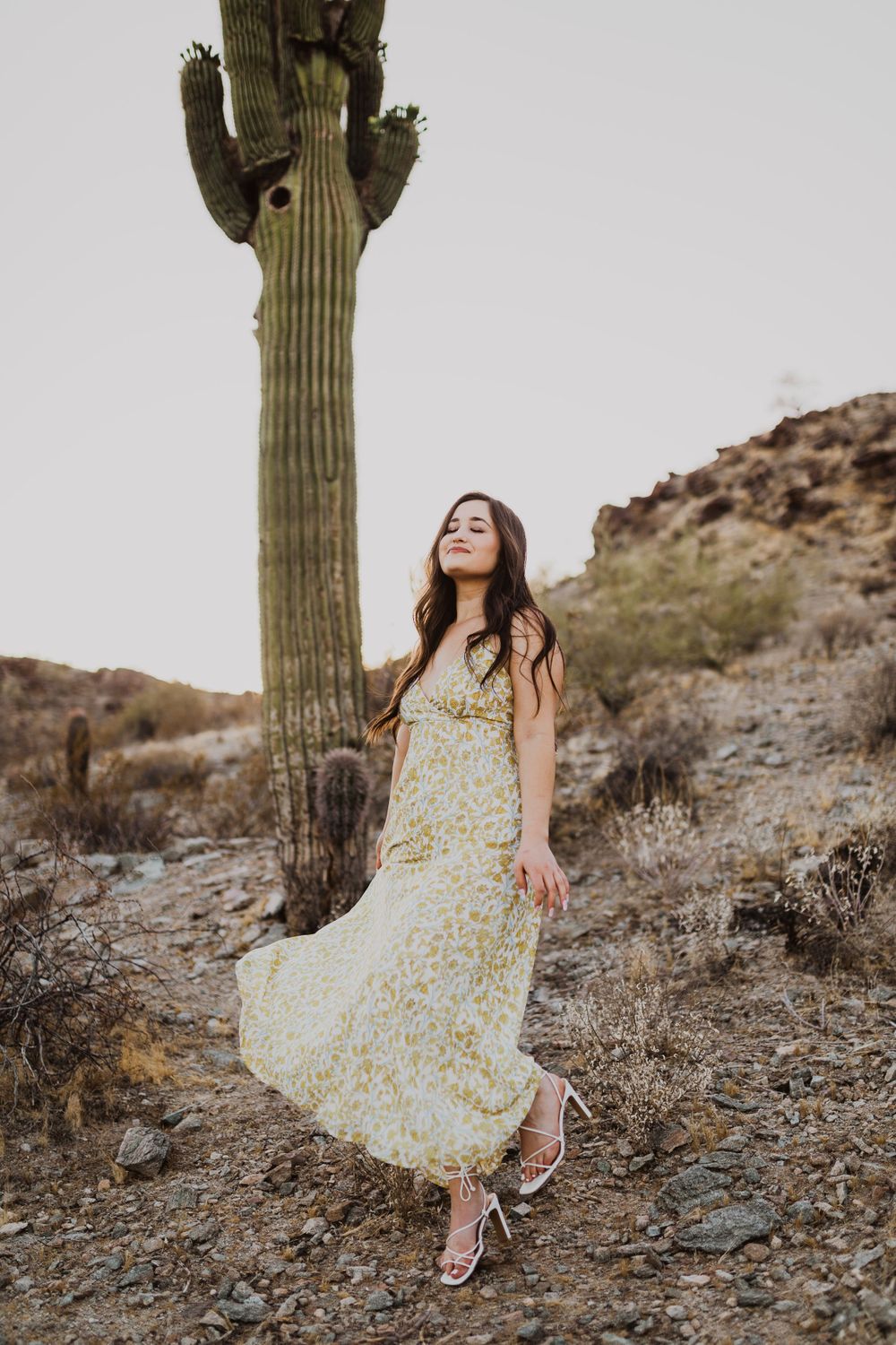 Desert fashion photography with flowing yellow dress against dramatic cactus backdrop.