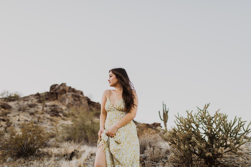 Desert landscape fashion photography with flowing dress and natural scenery.