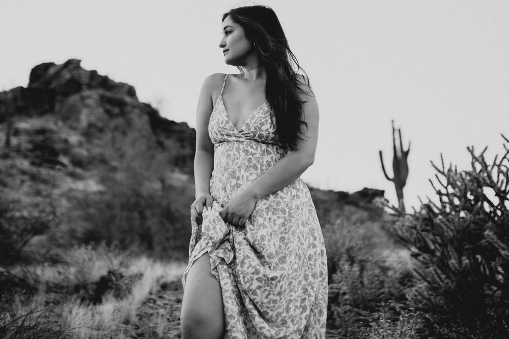 A flowing floral dress catches the desert breeze against a backdrop of rugged mountains and saguaro cacti.