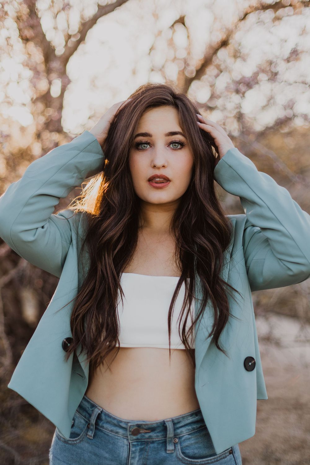 Fashion portraits featuring a mint blazer, white crop top and denim in natural lighting.